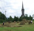 Des faucheurs à côté de l’église en bois de Plopiş, monument classé dans le patrimoine de l’UNESCO.